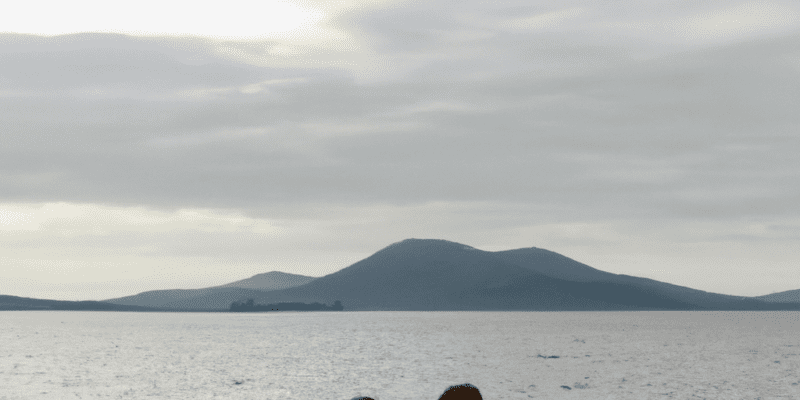 A picture of Sarah and Michael standing on the beach, looking out at the mysterious island in the distance.